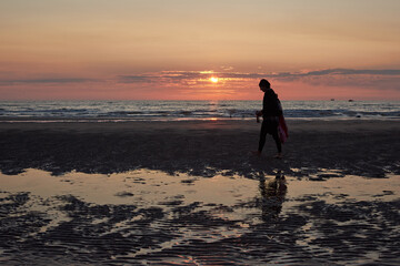 A rear view of a lady walking at the beach enjoying the scenic sunset