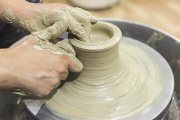 Fototapeta premium Ceramic Artist hands mold clay on pottery wheel. Arts creative workshop.