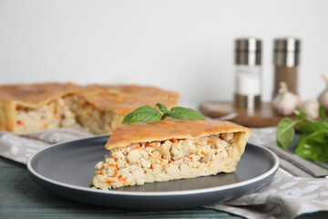 Slice of delicious meat pie with basil on blue wooden table, space for text