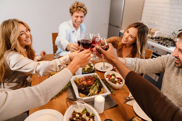 Multiracial happy friends drinking wine during thanksgiving dinner