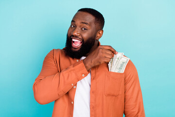 Photo of young black man happy positive smile rich currency dollars isolated over turquoise color...