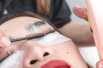 A beautician uses a lash roller to style the eyelash extensions of a customer.
