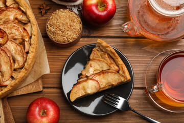 Delicious apple pie served with tea on wooden table, flat lay