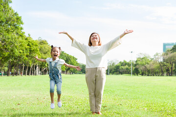 Asian elderly woman playing and raising her hands with little girl in the park with happy and smile