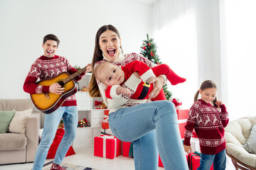Photo of cheerful positive couple two kids dressed new year pullovers smiling playing guitar...