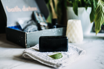 Lifestyle still life with black charcoal soap on beauty box background. Handmade soap with...