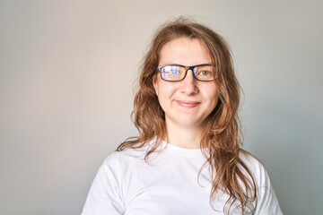 Fototapeta premium Young woman portrait. Pretty bussines face. Lifestyle happy emotions. White casual t-shirt. Looking at camera. Grey background. Copyspace. Adult people