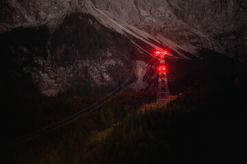 Power pole in dark forest at night in the alps