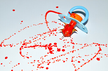 Baby's dummy with Drops of blood staining spots on a white background, medecine, drug addiction, killing
