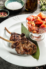 Grilled lamb carre with vegetable salad with tomatoes, ertical image. top view. place for text