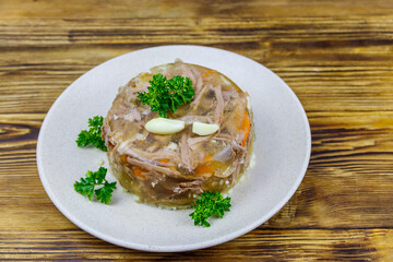 Meat aspic in a plate on a wooden table. Traditional russian dish