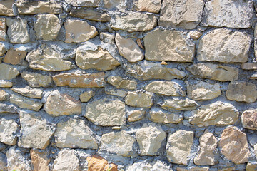 The rough textured surface of the wild stone wall. Background.