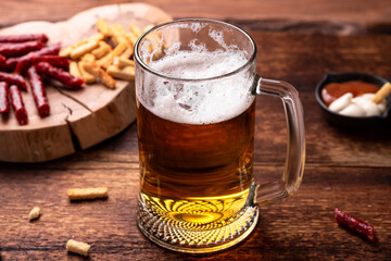 Glass of beer and snacks on a wooden background.