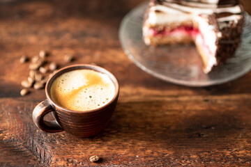 Cup of coffee and a piece of cake on a dark wooden background.