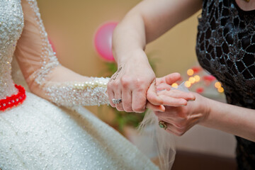 The bride ties a ribbon and money over her hand . He ties a ribbon and money over his hand.