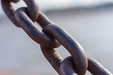 Heavy forged chain on the fence of the Neva embankment. The links of an old chain, illuminated by...