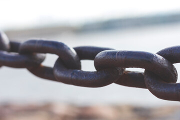 Heavy forged chain on the fence of the Neva embankment. The links of an old chain, illuminated by the sun, close-up.