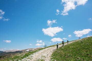 a group of people goes hiking with backpacks in mountains Caucasus, bright blue sky, valley with snow