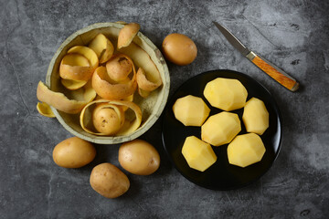 peeled potatoes on black plate - gray background - closeup
