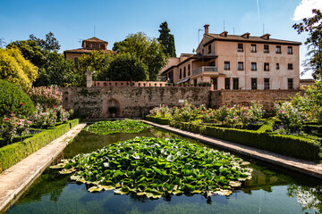 Fototapeta premium View from over the pool at the Ladies Tower (Torre de las Damas, Partal Palace) towards the Garden of the Partal, Nasrid palaces, Alhambra de Granada UNESCO World Heritage Site, Andalusia, Spain