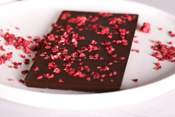 chocolate with dry raspberries lies on a light background