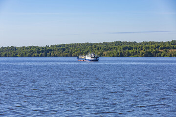 Fototapeta na wymiar An old oil tanker sails along the Volga river near the forest shore. Yaroslavl Region, Russia
