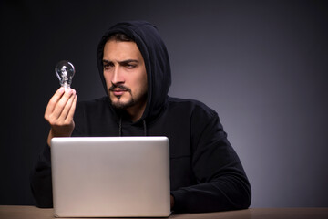 Young male hacker on grey background