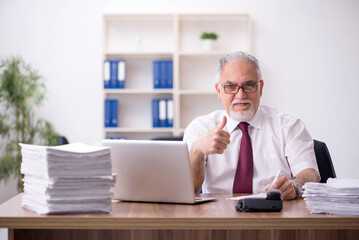 Obraz premium Old male employee and too much work in the office