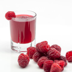 glass with raspberry alcoholic drink and raspberries on white background  