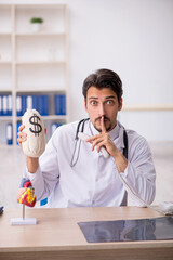 Young male doctor cardiologist holding monebag