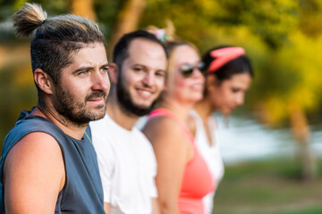 Selective focus on a man standing and resting with a group of friends in a park