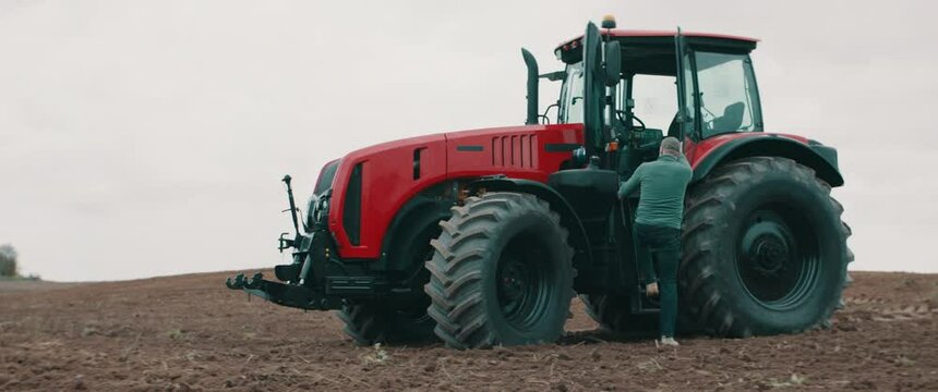 Hero shot portrait of 50s farmer walking towards tractor early in the morning in the field. Shot with 2x anamorphic lens