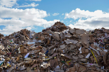 Photo of a large amount of garbage and rubbish at the dump in the street under the blue sky with white clouds