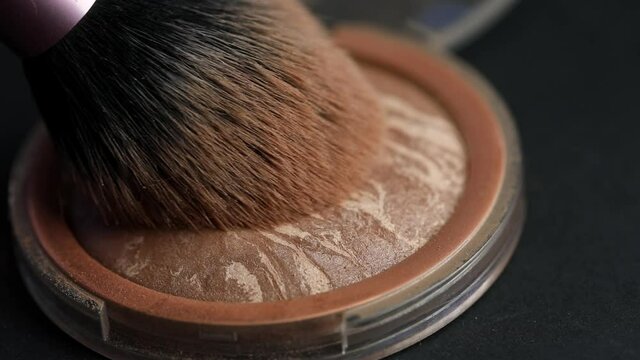 Makeup artist applies facial contour, bronzer on a large lush makeup brush, close-up. The concept of using working beauty tools