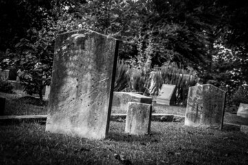 A black and white photograph of grave stones in a creepy cemetery. 