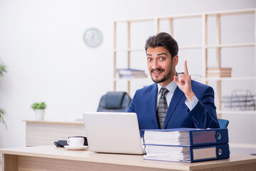 Obraz premium Young handsome employee working in the office