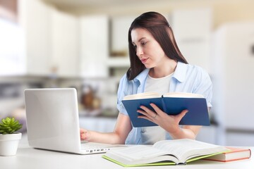 Caucasian female student working from home writing, sitting next to books