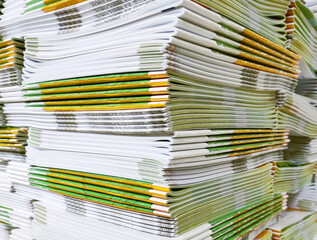 Lot of books stacked in layers in huge endless wall of knowledge. Industrial printing house. Book spines folded into stacks before trimming. Library background, typography, bookstore. Corner view