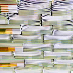 Lot of books stacked in layers in huge endless wall of knowledge. Industrial printing house. Book spines folded into stacks before trimming. Library background, typography, bookstore. Front view
