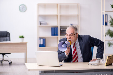 Angry boss holding megaphone at workplace