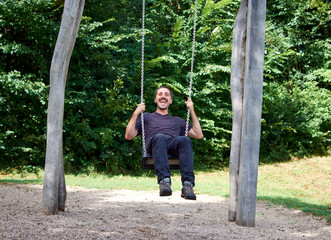 A young Hispanic man on a swing in a park