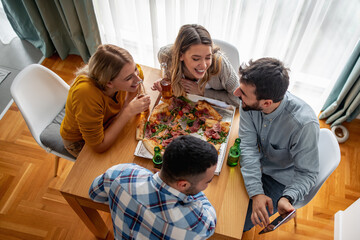 Friends eating pizza at home party