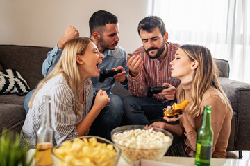 Happy friends playing video games at home