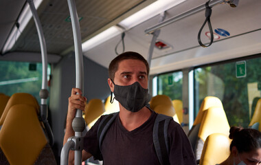 A young Hispanic male with a medical face mask on a bus