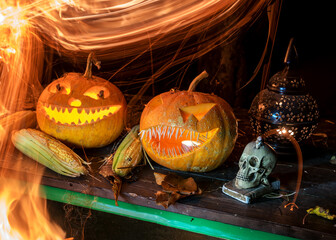 carved pumpkins surrounded by sparks, smoke and fire, Halloween composition with smiling pumpkins...