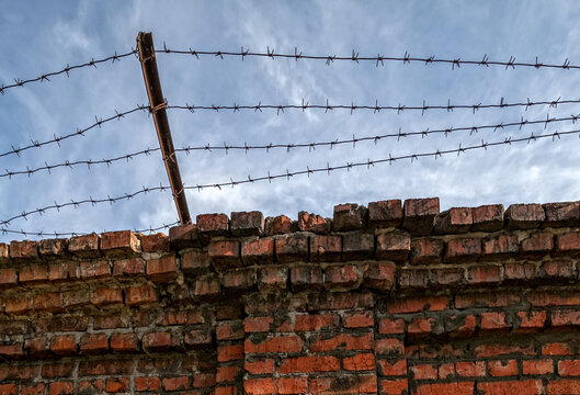barbed wire on a brick wall. red brick wall and blue sky