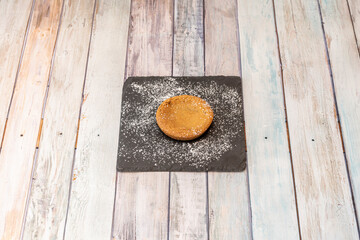 Chocolate filled cookie with glass sugar on top on black slate plate on wooden table