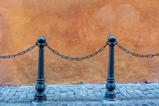 Historic black metal chain fence against an ocker colored wall in a narrow city street