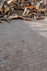 Pile of firewood lies on paving slabs