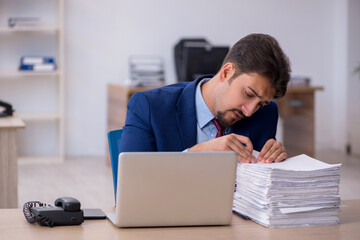 Fototapeta na wymiar Young businessman employee and too much work in the office
